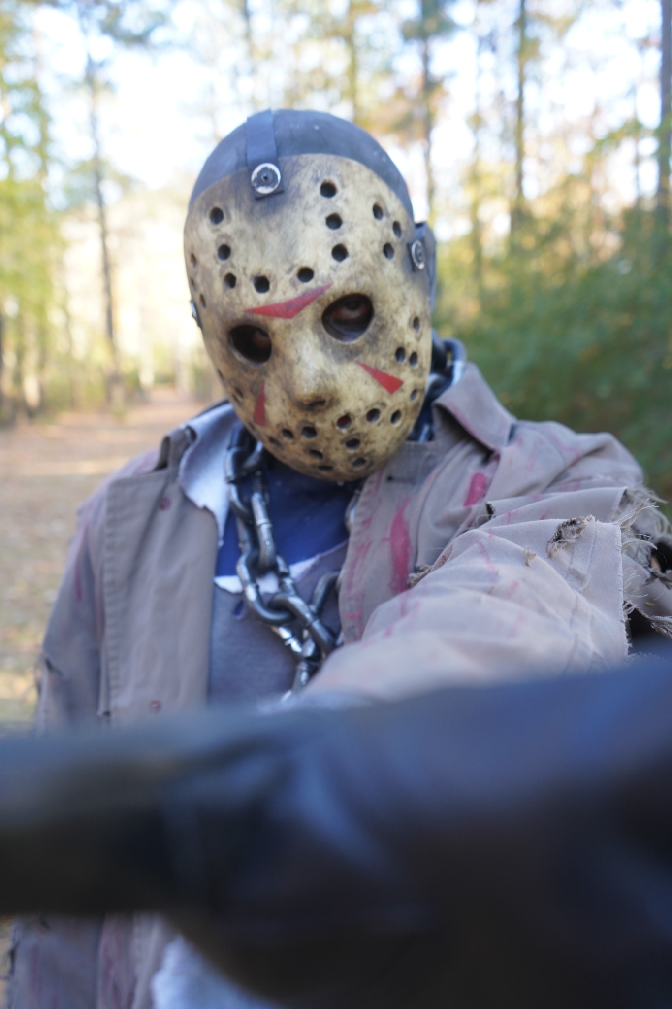 Masked scare actor facing the camera in a distressed costume