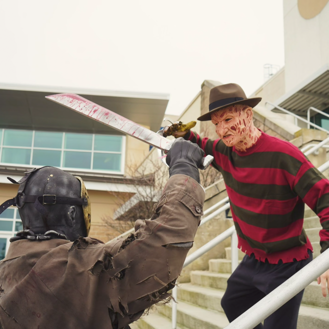 Nicolas and a friend in horror costumes posing together with a prop machete