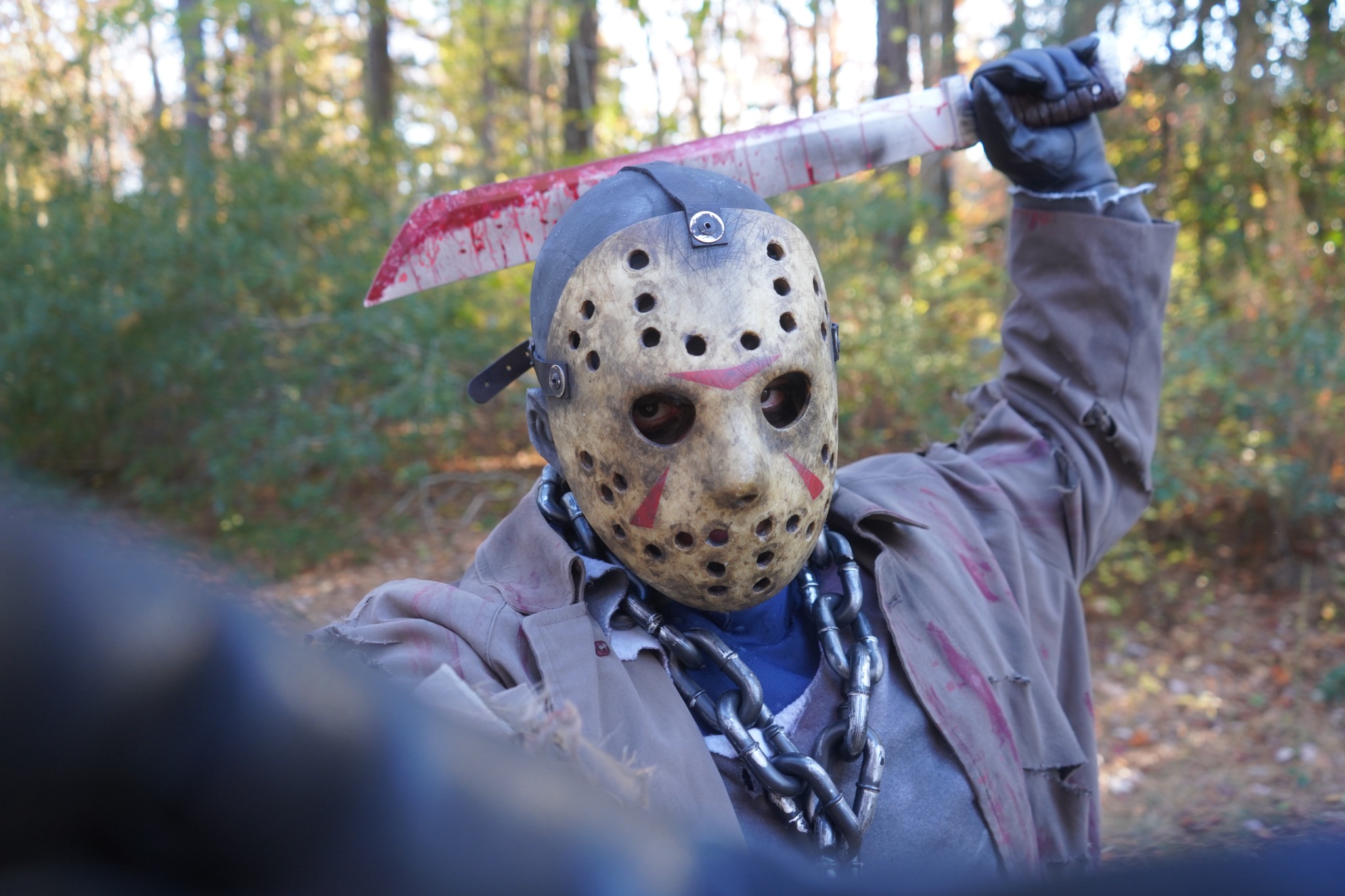 Masked scare actor posing with a prop machete